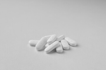 Pile of calcium supplement pills on light grey background