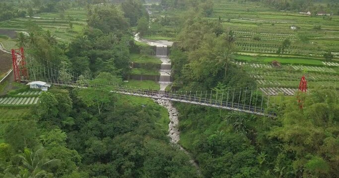 Aerial drone view of suspension bridge, valley and river with waterfalls. mangunsuko bridge or Jokowi bridge. infrastructure videos