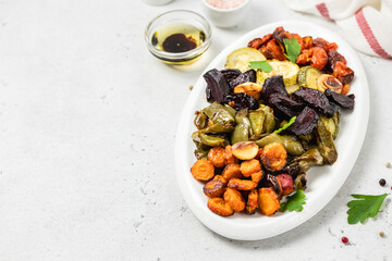Healthy diet, roasted vegetables on white dish. Top view, flat lay, copy space.