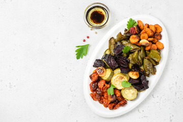 Roasted summer side dish, vegetables on white plate. Top view, flat lay, copy space.