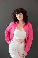 oung happy girl with crooked teeth and cute facial expression with voluminous curly hair poses in...