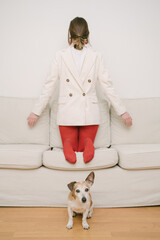 introvert behavior. a girl in red tights and a jacket stands back to front on the couch. a small...