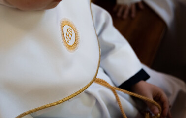 IHS Christian symbol on a communion child. IHS Christogram embroidered with gold thread on a white...