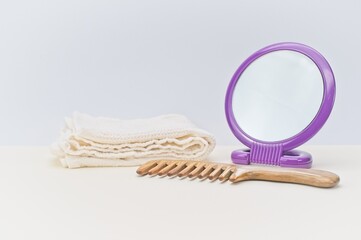 white cotton towel, hair wooden comb and mirror on a bright desk