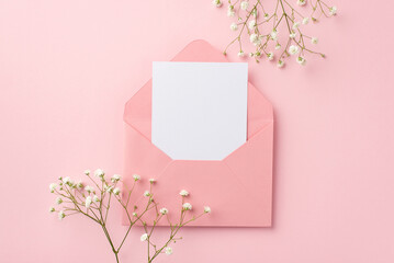 Wedding invitation concept. Top view photo of open pink envelope with paper card and white gypsophila flowers on isolated pastel pink background with empty space