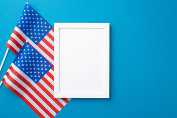 USA Independence Day concept. Top view photo of white photo frame and national flags on isolated blue background with copyspace