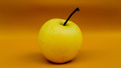 A pear with stem on orange background