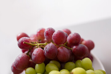 Fresh red and green grape on plate, close-up. Healthy lifestyle concept.