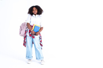 In full growth, young African American teenager girl in white headphones,  white  t-shirt and blue jeans with backpack and books mockup in hands posing on white background. Studio photo. Generation Z