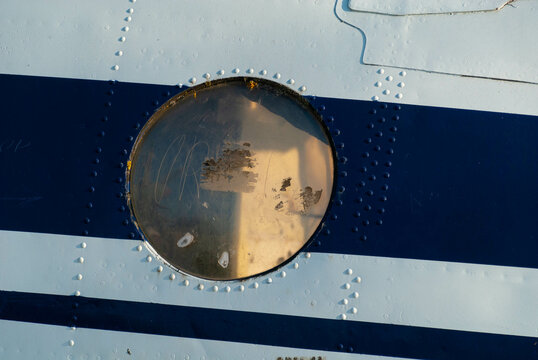 An Old Airplane Window With Dirty Scratched Glass On The Skin Of An Abandoned Plane