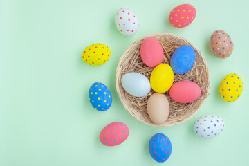 Colorful eggs in a basket on green background