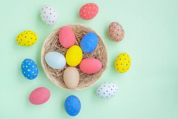 Colorful eggs in a basket on green background