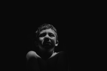 Black and white portrait of sad anonymous little boy crying