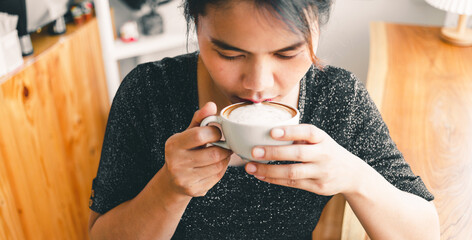 Closeup of a beautiful girl smelling and drinking hot coffee with feeling good in cafe she enjoys...