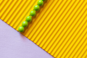 top view of green balls on textured yellow and violet background.