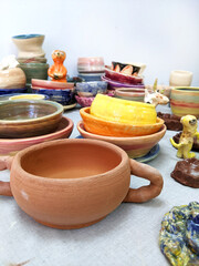 Ceramic cups, mugs and pots on a table in a pottery workshop.