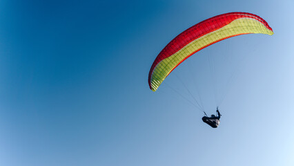 Paraglider in the blue sky. The sportsman flying on a paraglider.