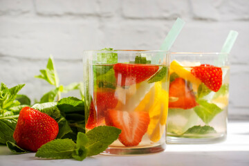 Lemonade with strawberries, mint, lemon on a light background