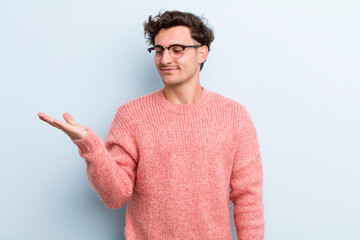 young handsome man feeling happy and smiling casually, looking to an object or concept held on the...
