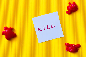 top view of red toy marine animals near blue paper with kill inscription on yellow background.