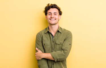 young handsome man laughing shyly and cheerfully, with a friendly and positive but insecure attitude