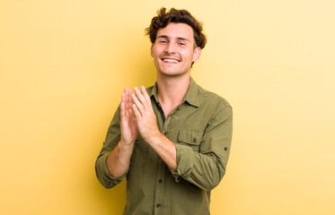 young handsome man feeling happy and successful, smiling and clapping hands, saying congratulations...