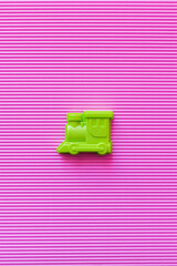 top view of bright green toy locomotive on violet textured background.