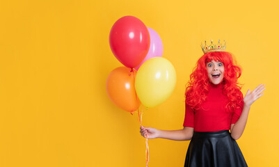 happy child in crown with helium balloon on yellow background. wow