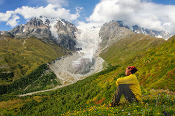 Fototapeta na wymiar A man in a yellow jacket looks at the Adishi Lardaad glacier in Georgia. Svaneti.