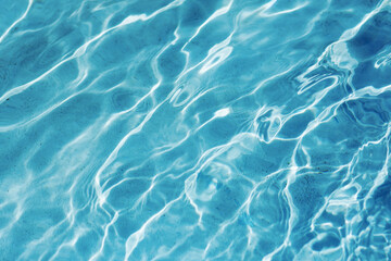 Fototapeta na wymiar Blue water background of swimming pool or sea. Ripple water in swimming pool with sun reflection.
