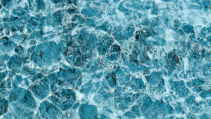 Blue water background of swimming pool or sea. Ripple water in swimming pool with sun reflection.