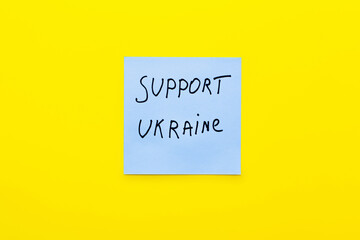 top view of paper with support ukraine lettering on bright yellow background.