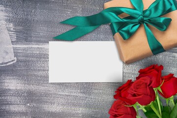Valentines day concept. White greeting card with red rose flowers bouquet and gift box on stone table