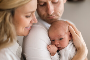 Smiling mother and father holding their newborn baby daughter at home