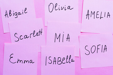 top view of sticky notes with different female names on violet background.
