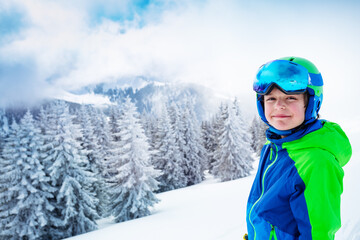 Fototapeta na wymiar Boy in ski outfit smiling portrait over forest after snowfall