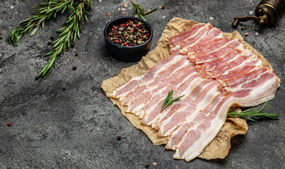 Raw bacon, bacon strips meat slice thin slicing pork fat meal on a dark background, ketogenic diet, place for text, top view