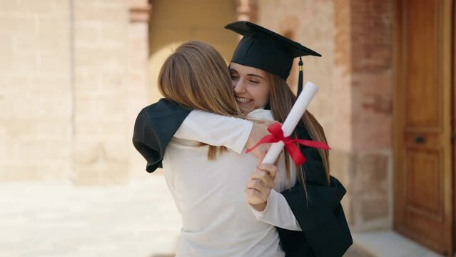 Two women mother and graduated daughter standing together at campus university