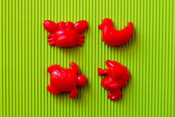 top view of red sea animals and duck toys on green corrugated background.