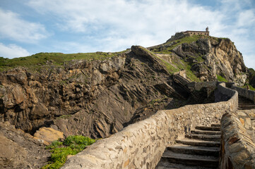 Stone footpath to famous landmark and film location in North of Spain, ocean islet with chapel San...