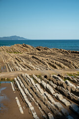 View on steeply-tilted layers of flysch on Atlantic coast at Zumaia at low tide, Basque Country, Spain