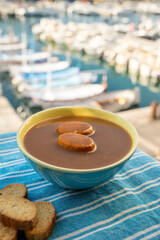 Homemade fish soup with croutons served with view on colorful fisherman's boats in harbour of Cassis, Privence, France.