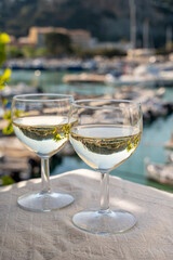 Two glasses of white wine from Cassis region served on outdoor terrace with view on old fisherman's harbour with colourful boats in Cassis, Provence, France