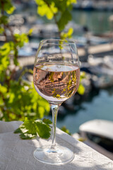 Rose wine in glass served on outdoor terrace with view on old fisherman's harbour with colourful boats in Cassis, Provence, France