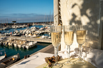 Three glasses of French champagne sparkling wine and view on colorful fisherman's boats in old harbour in Cassis, Provence, France