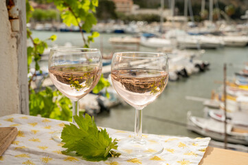 Rose wine in glasses served on outdoor terrace with view on old fisherman's harbour with colourful boats in Cassis, Provence, France