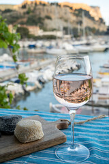 Rose wine in glass served with goat cheeses on outdoor terrace with view on old fisherman's harbour...