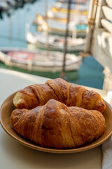 Summer morning in Provence, breakfast with fresh baked croissants and view on fisherman's boats in harbour of Cassis, Provence, France