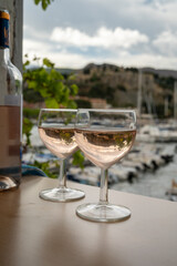 Rose wine in glasses served on outdoor terrace with view on old fisherman's harbour with colourful boats in Cassis, Provence, France