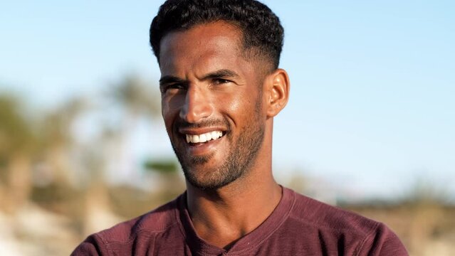 Handsome and confident, outdoor smiling portrait of relaxing young african egyptian man traveler on the beach.